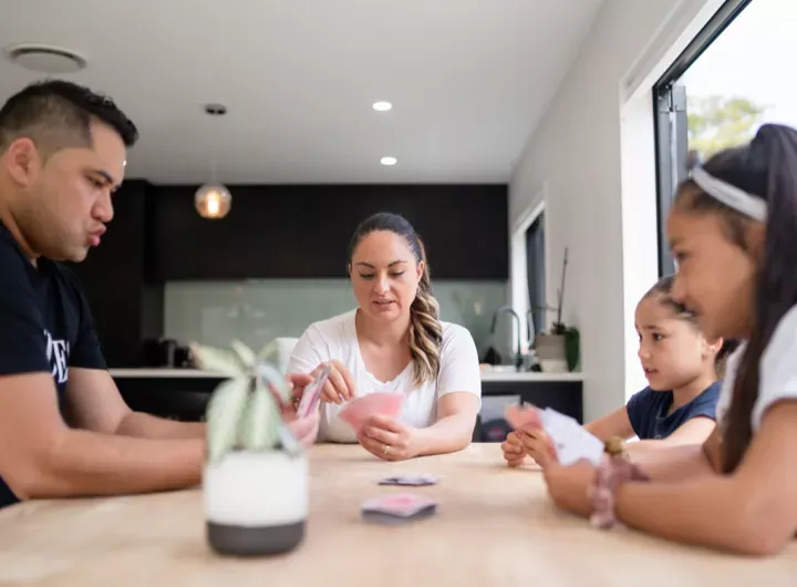 A family gathered around a table playing a card game together in a modern kitchen.